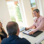 couple negotiating a house price with a seller at a desk